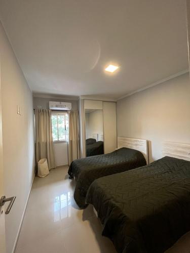 a hotel room with two beds and a window at Departamento Quality Belgrano in Santiago del Estero