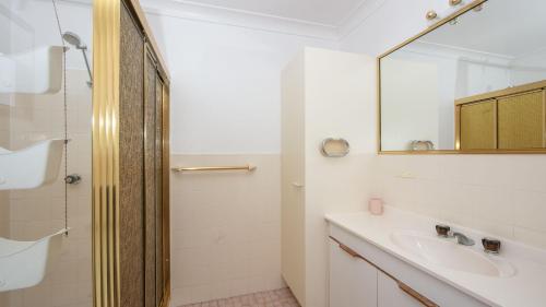 a white bathroom with a sink and a mirror at Waratah in Iluka