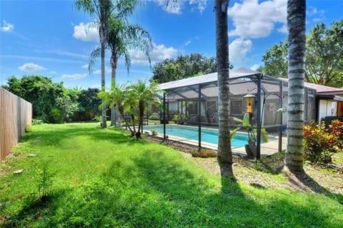 a house with a swimming pool and palm trees at Florida Oasis in Auburndale