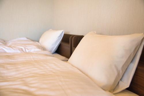 an unmade bed with two pillows in a bedroom at Tabist Hotel Chouseikaku in Yatsushiro