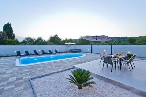 a patio with a table and chairs and a pool at Villa Blazen in Bogomolje