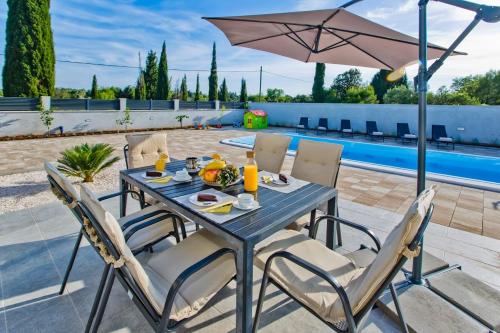 a table with chairs and an umbrella on a patio at Villa Blazen in Bogomolje