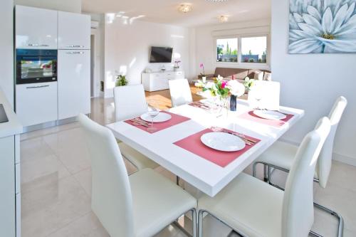 a white dining room with a white table and white chairs at Villa Blazen in Bogomolje