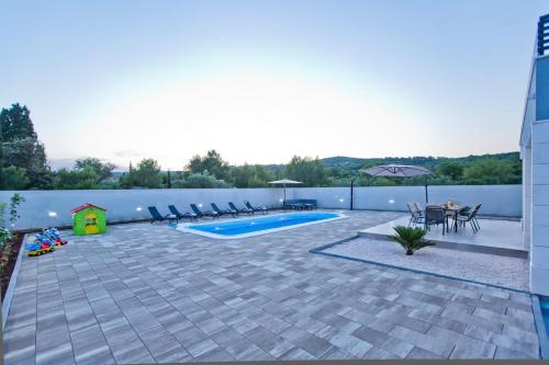 a backyard with a swimming pool and patio furniture at Villa Blazen in Bogomolje