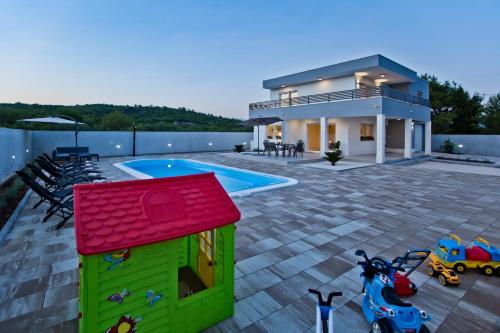 a house with a toy dog house and a swimming pool at Villa Blazen in Bogomolje
