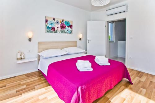 a bedroom with a pink bed with two towels on it at Villa Blazen in Bogomolje
