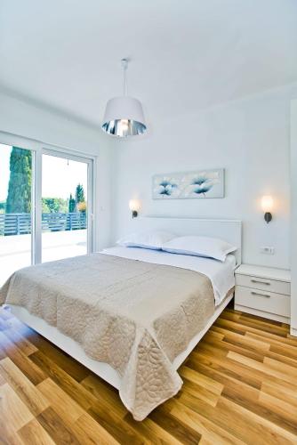 a white bedroom with a large bed and a window at Villa Blazen in Bogomolje
