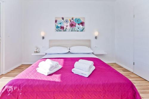 a bedroom with a pink bed with two white towels at Villa Blazen in Bogomolje