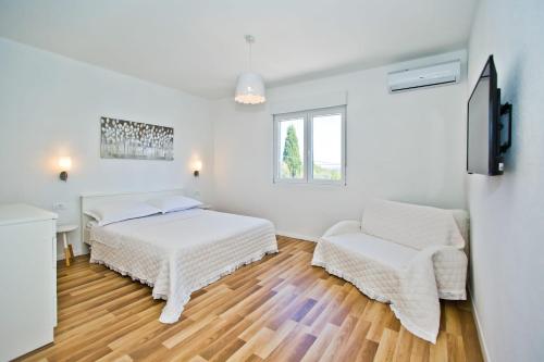 a white room with two beds and a chair at Villa Blazen in Bogomolje