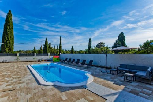 a swimming pool on a patio with chairs and a fence at Villa Blazen in Bogomolje