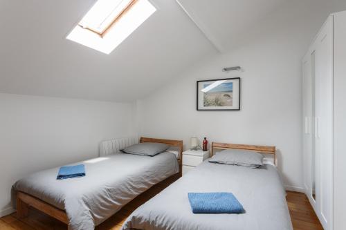 Ce lit se trouve dans un dortoir doté de murs blancs et d'une lucarne. dans l'établissement Maison de ville le blanc mesnil, au Blanc-Mesnil