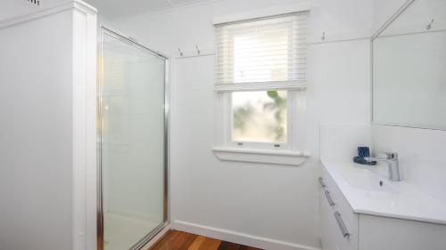 baño blanco con ducha y ventana en Koala Lodge Cottage 5, en Iluka