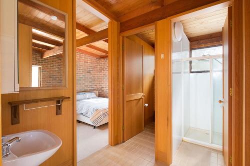 ein Badezimmer mit Waschbecken und ein Bett in einem Zimmer in der Unterkunft Shearwater Beach House in Silverleaves in Cowes