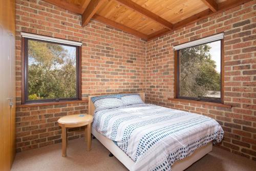 ein gemauertes Schlafzimmer mit einem Bett und 2 Fenstern in der Unterkunft Shearwater Beach House in Silverleaves in Cowes