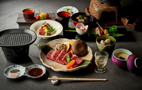 a table topped with plates of food and chopsticks at Shima-Onsen Toshimaya in Nakanojo