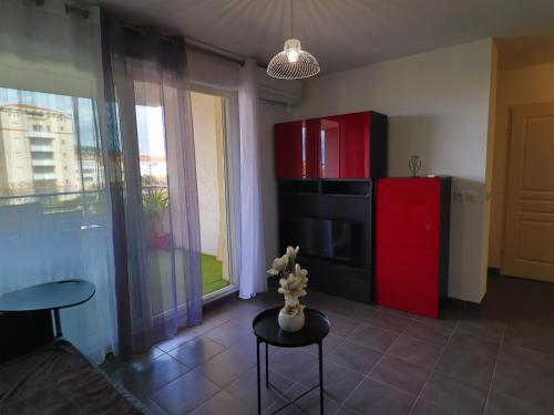 Il comprend une cuisine équipée d'un réfrigérateur rouge et d'une table. dans l'établissement Charmant 2 pièces avec clim, parking et piscine, à 300m de la plage - Sète - FR-1-472-189, à Sète