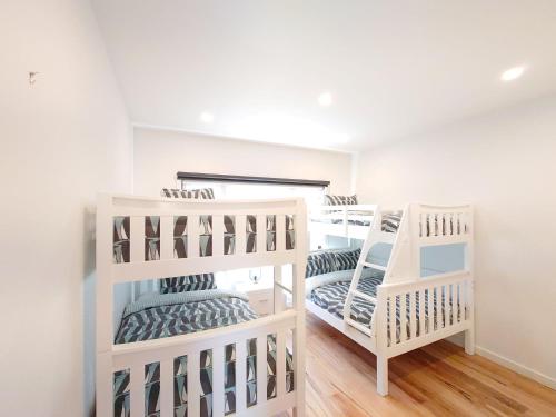 two white bunk beds in a room with wood floors at Beachcomber Sunset in Smiths Beach