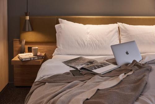 a bed with a laptop computer and books on it at Rydges Melbourne in Melbourne