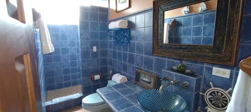 Baño de azulejos azules con lavabo y espejo en Gone Fishing Panama Resort, en Boca Chica