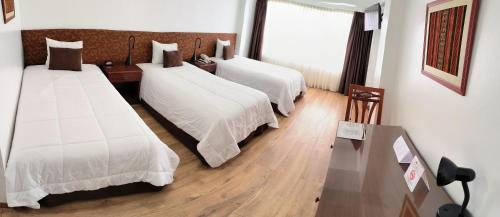 a hotel room with two beds and a table at Faraona Grand Hotel in Lima