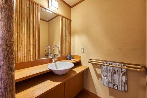 a bathroom with a sink and a large mirror at Shima-Onsen Toshimaya in Nakanojo