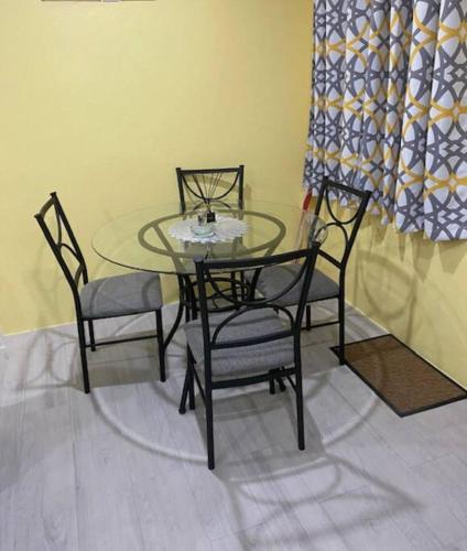 a glass table with four chairs and a glass table with a glass at Hidden Zen 108 with rental vehicle access in Castries