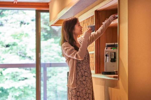 a woman is reaching into a cabinet in a kitchen at Shima-Onsen Toshimaya in Nakanojo
