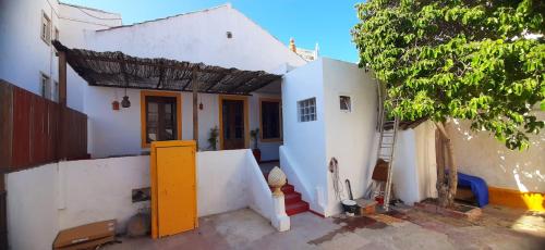 una casa blanca con una puerta amarilla y un árbol en Hostel A Casa da Árvore, en Faro