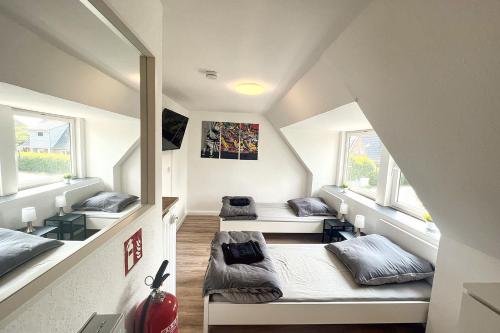 una camera mansardata con tre letti e finestre di Apartments in Trittau near Hamburg a Trittau