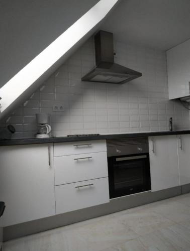 a kitchen with white cabinets and a stove top oven at El pisin de Claudia in Colombres