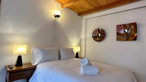 1 dormitorio con 1 cama blanca y reloj en la pared en Casa Clásica con Chimenea!, en Villa de Leyva