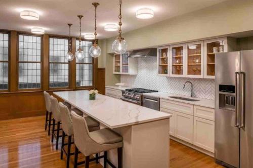 a kitchen with white cabinets and a large island with bar chairs at Beautiful Condo/Rooftop Patio With Free Parking in Cleveland