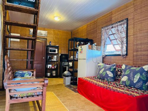 Cette chambre comprend un réfrigérateur, un canapé et une chaise. dans l'établissement moorea temae bungalow lory bord de mer, à Moorea