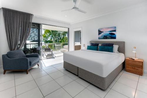 Blue Water Views 16 - 3 Bedroom Penthouse with Ocean Views في جزيرة هاميلتون: غرفة نوم بسرير كبير وكرسي