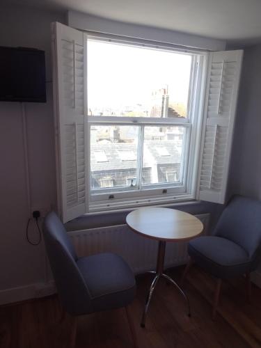 a room with a table and two chairs and a window at Aquarium Guest House in Brighton & Hove