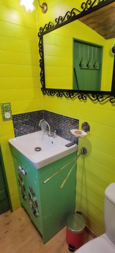 une salle de bain avec un lavabo vert et un miroir dans l'établissement roulotte Tipergwendiou, à Plougonvelin