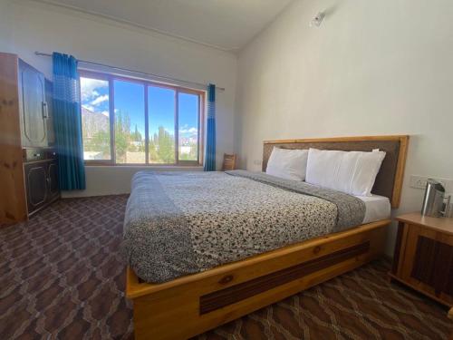 a bedroom with a bed and a large window at Otsal guest house nubra in Deskit