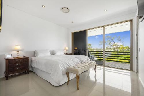 a white bedroom with a bed and a large window at 8 On Weyba in Noosaville