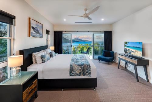 a bedroom with a bed and a television and a balcony at La Bella Waters 5 Oceanview Private Garden BBQ Buggy in Hamilton Island