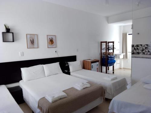 a white room with two beds and a chair at Hotel Pousada Santa Maria in Aparecida