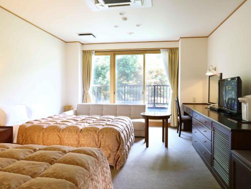 a hotel room with a bed and a window at Yugawara Chiyodasou in Yugawara