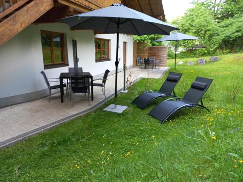 a group of chairs and an umbrella in the grass at Ferienwohnung am Wald in Waidring