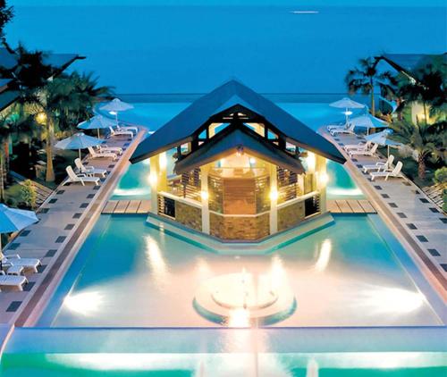 Acuatico Beach Resort & Hotel Inc. في سان خوان: منتجع فيه مسبح وبه كراسي ومبنى