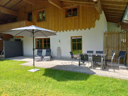 a patio with a table and chairs and an umbrella at Ferienwohnung am Wald in Waidring