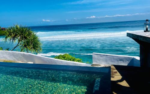 a swimming pool with the ocean in the background at The Palms Ceningan Hotel in Nusa Lembongan