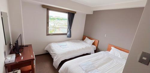 una camera d'albergo con due letti e una finestra di World Business Hotel a Iida