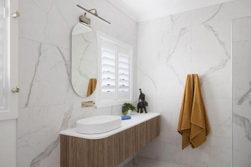 a white bathroom with a sink and a mirror at Little Beach Boutique Apartment Pet Friendly in Nelson Bay