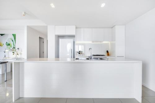 a white kitchen with a large white counter top at Darwin Waterfront Short Stay Apartments in Darwin