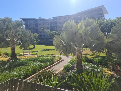 a park with palm trees in front of a building at Darwin Waterfront Short Stay Apartments in Darwin
