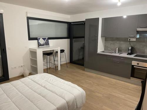 a bedroom with a bed and a desk and a kitchen at Parking gratuit grande terrasse Proche Centre Ville in Ajaccio